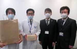 サージカルマスク500枚を寄贈いただきました）よりマスクを受け取る波呂感染制御部長（左）