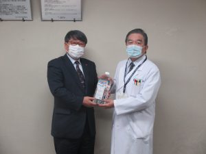 田中代表取締役社長（左）からアルコール製剤を受取る武田病院長（右）